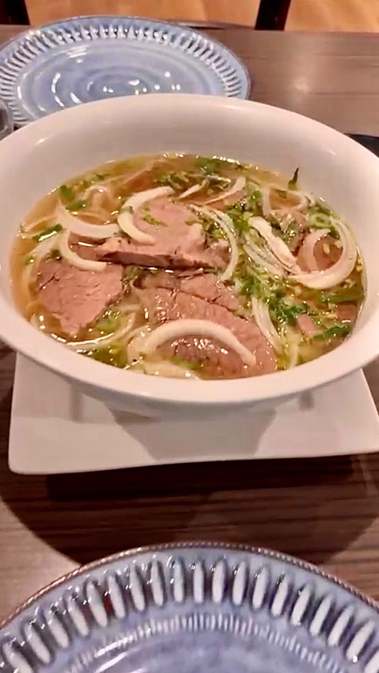 A bowl of beef pho with fresh herbs, lime and chilli