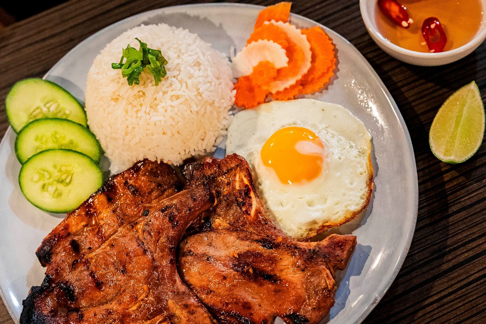 Broken rice with a grilled pork chop, fried egg, cucumber and pickles